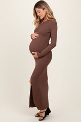 woman wearing a brown ribbed maternity maxi dress with a side slit and holding her baby bump