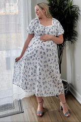 woman wearing a white floral maternity dress with a square neckline and puff sleeves, showing her baby bump