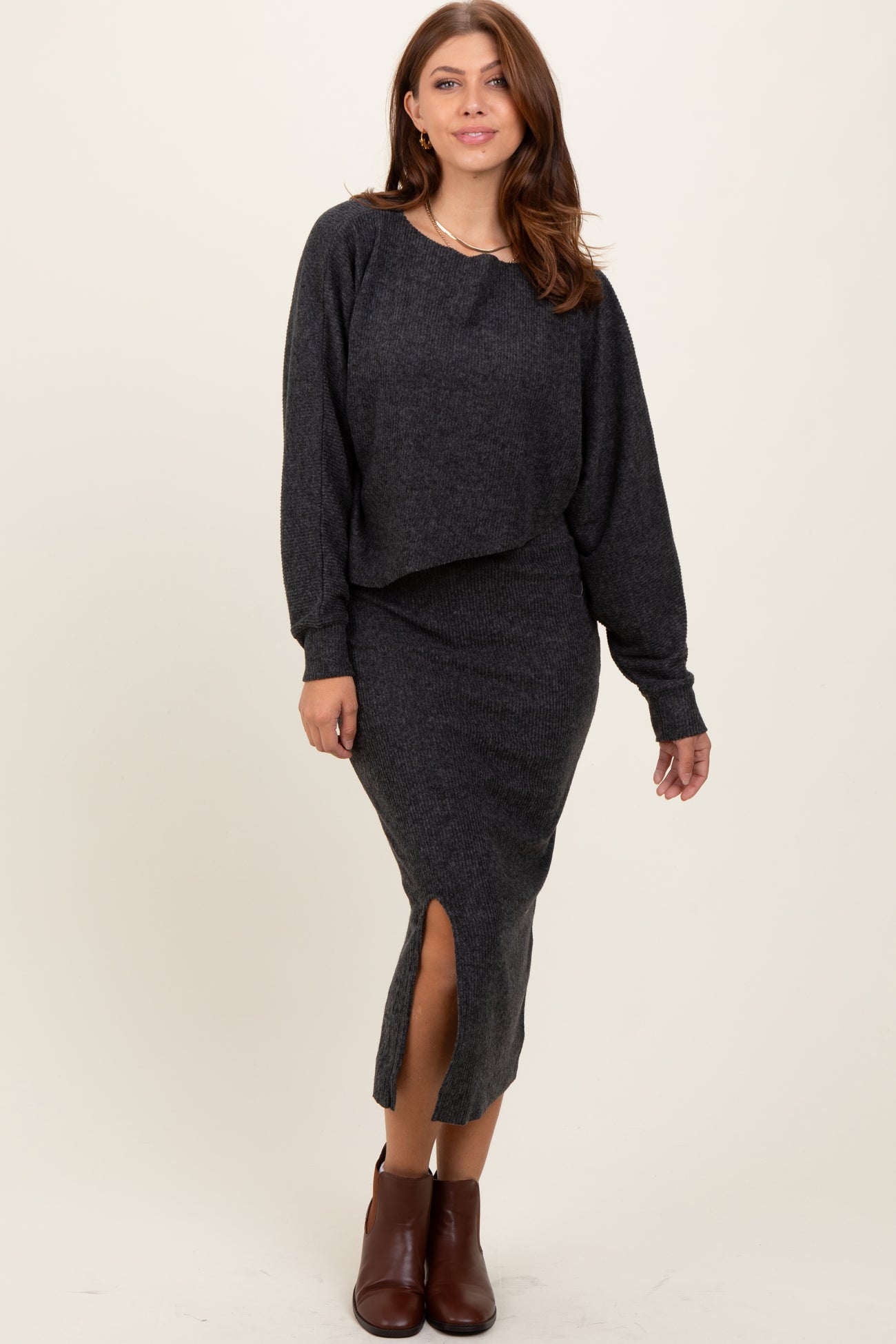 woman wearing a dark gray cropped sweater and matching midi skirt with a side slit