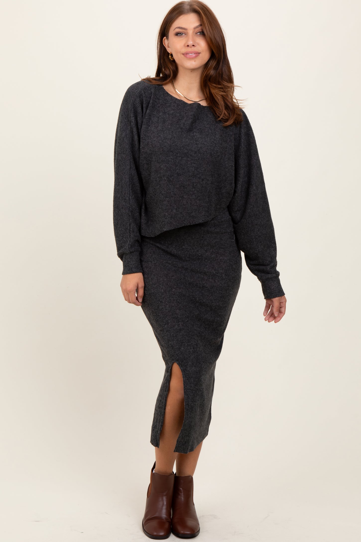 woman wearing a dark gray cropped sweater and matching midi skirt with a side slit