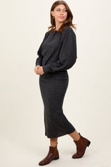 woman wearing a dark gray ribbed sweater and matching midi skirt, paired with brown ankle boots