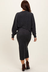 woman wearing a dark grey long sleeve fitted dress with a cropped sweater over it, seen from the back