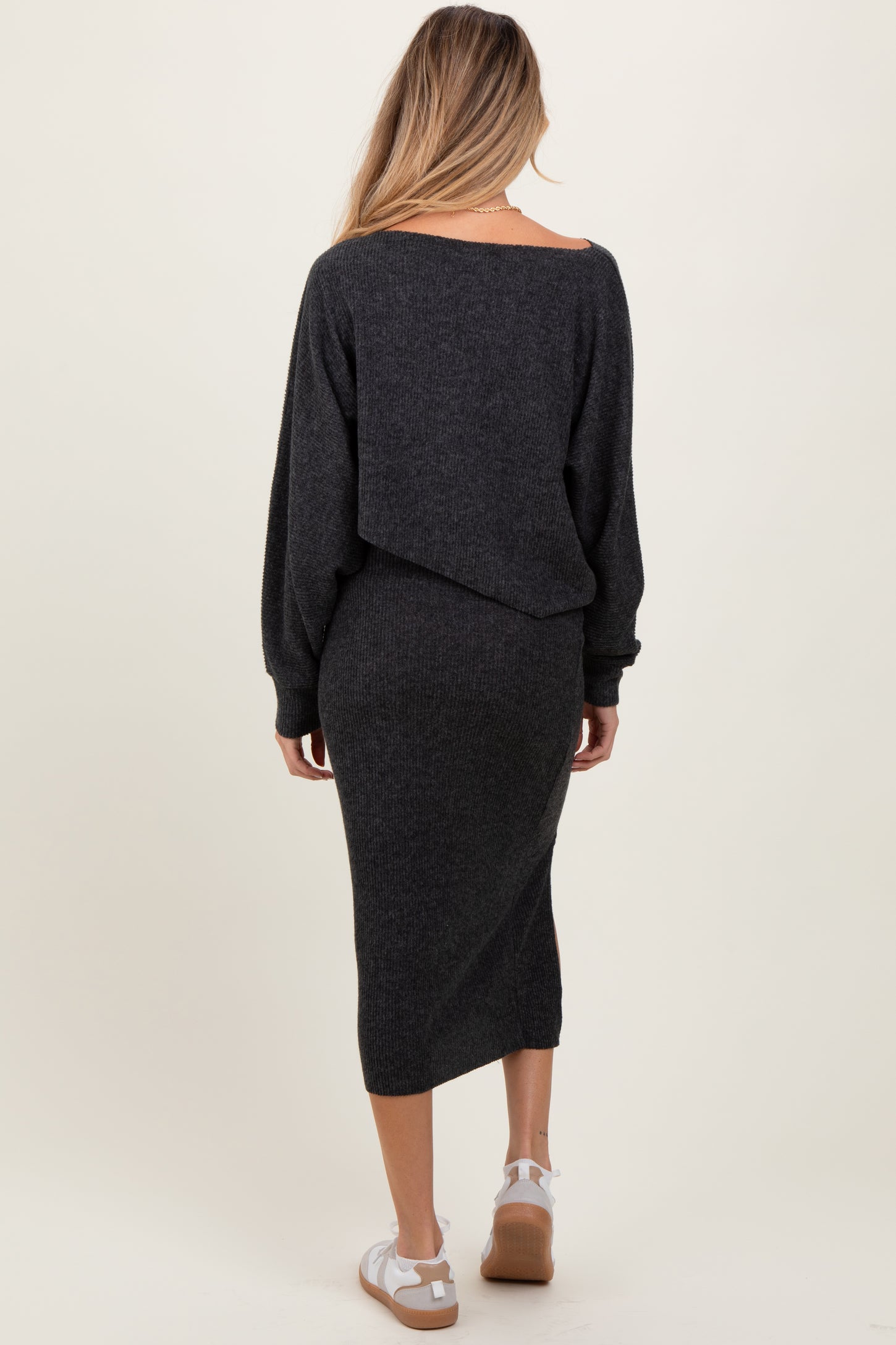 woman wearing a dark gray maternity sweater dress with an off-the-shoulder design and long sleeves