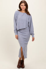 woman wearing a light gray two-piece ribbed sweater dress with a cropped top and a midi skirt featuring a side slit