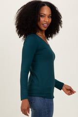 woman wearing a teal long sleeve top with a v-neck and side ruching, paired with blue jeans