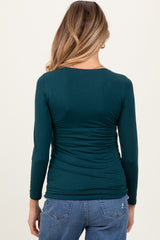 woman wearing a teal long sleeve maternity top with ruched detailing, viewed from the back