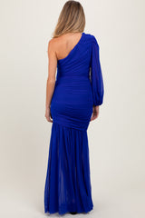 woman wearing a royal blue one-shoulder maternity dress with ruched detailing and a flowy skirt