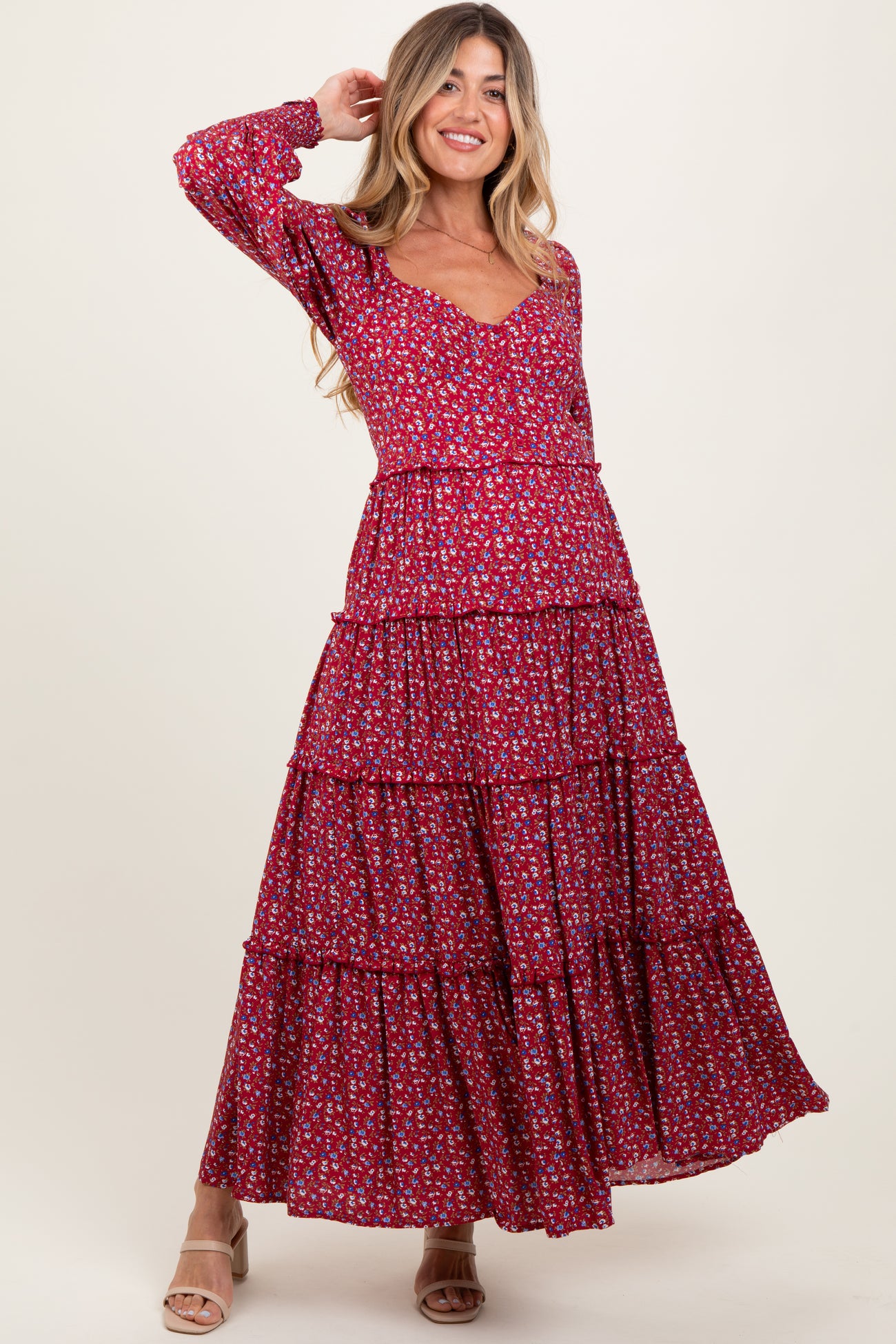 woman wearing a red floral tiered maxi dress, showcasing a v-neckline and long sleeves, with a visible baby bump