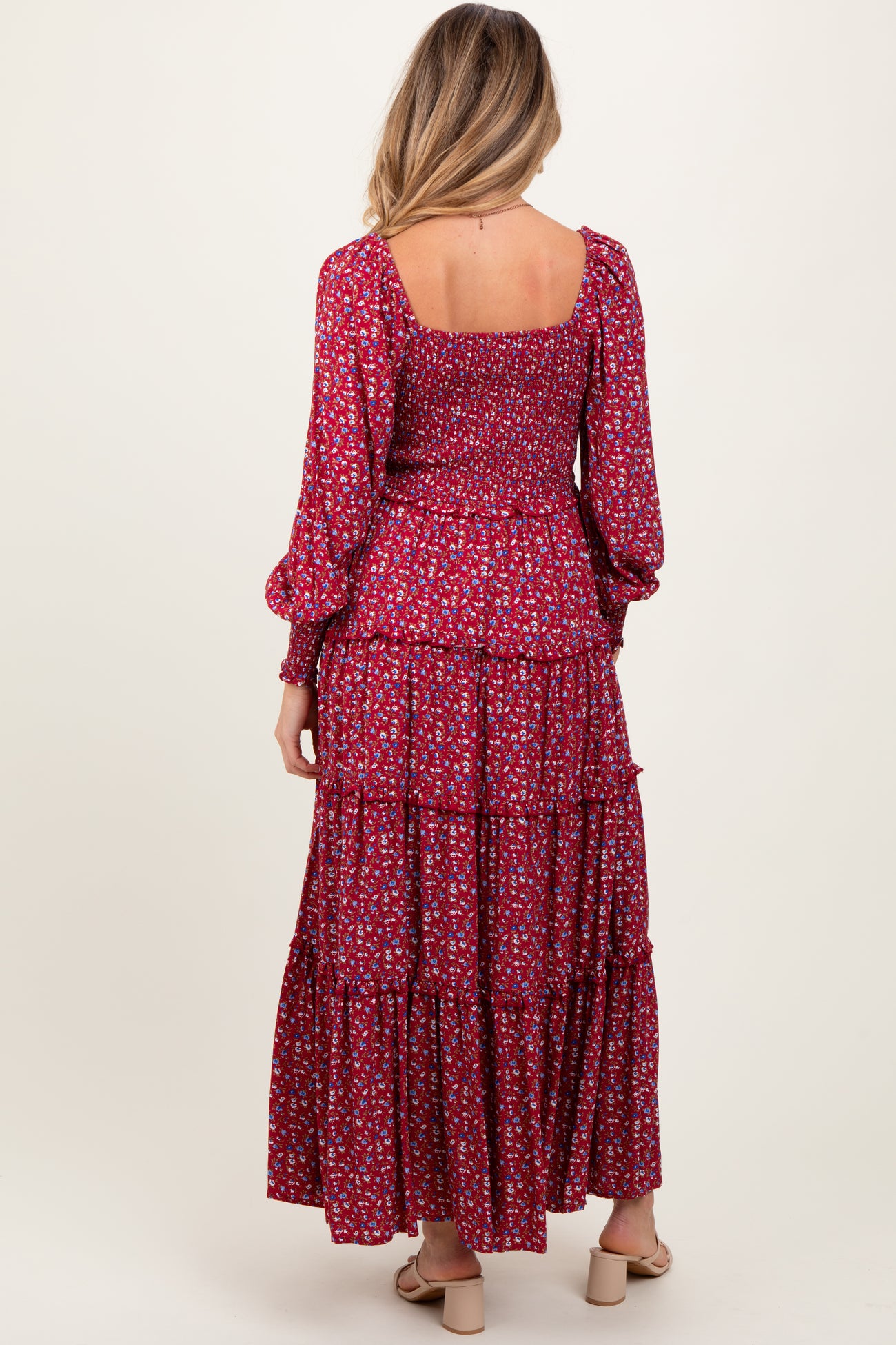 woman wearing a red floral maternity maxi dress with long sleeves and a tiered skirt, showing a baby bump from the back