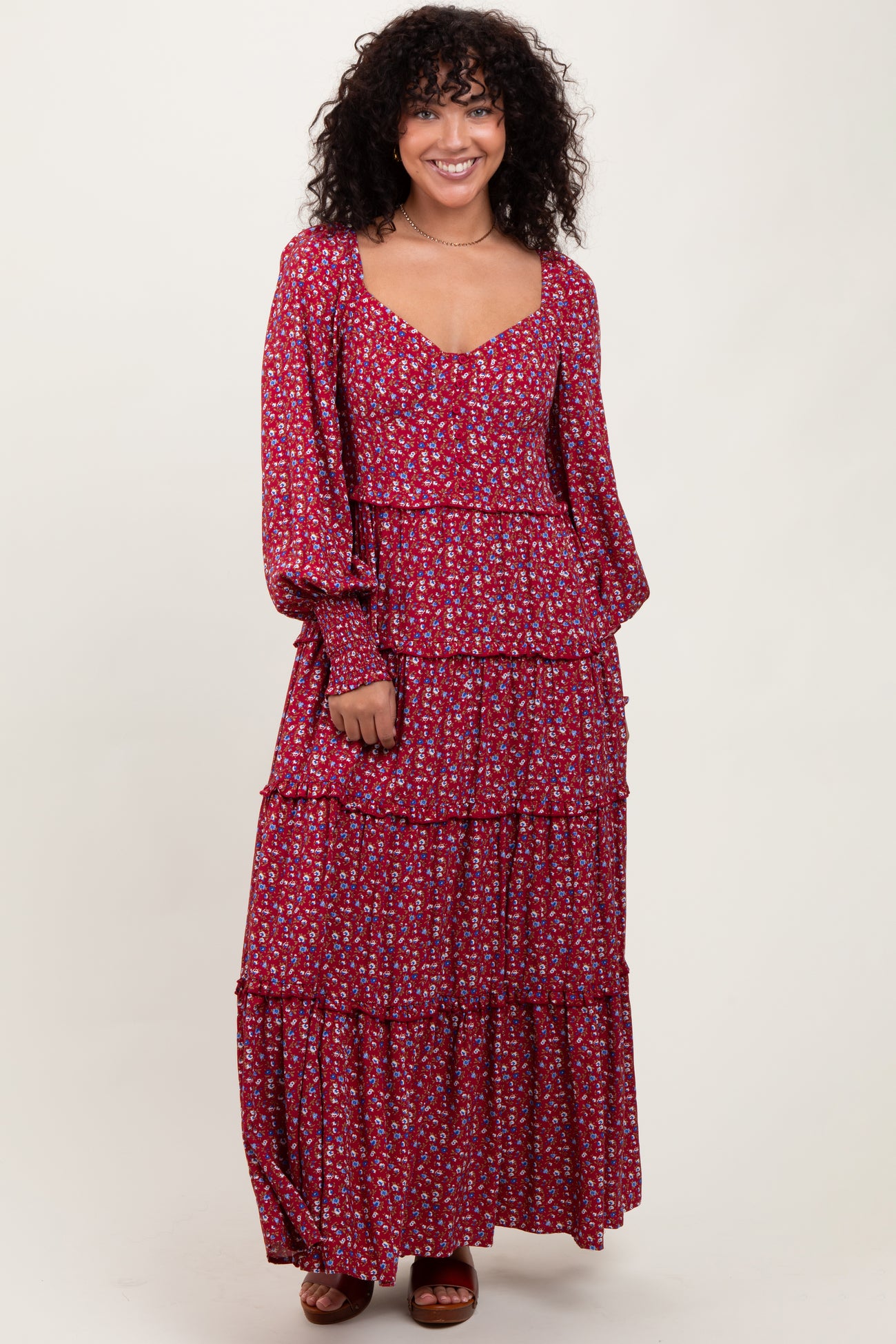 woman wearing a red floral tiered maxi dress with long sleeves and a scooped neckline