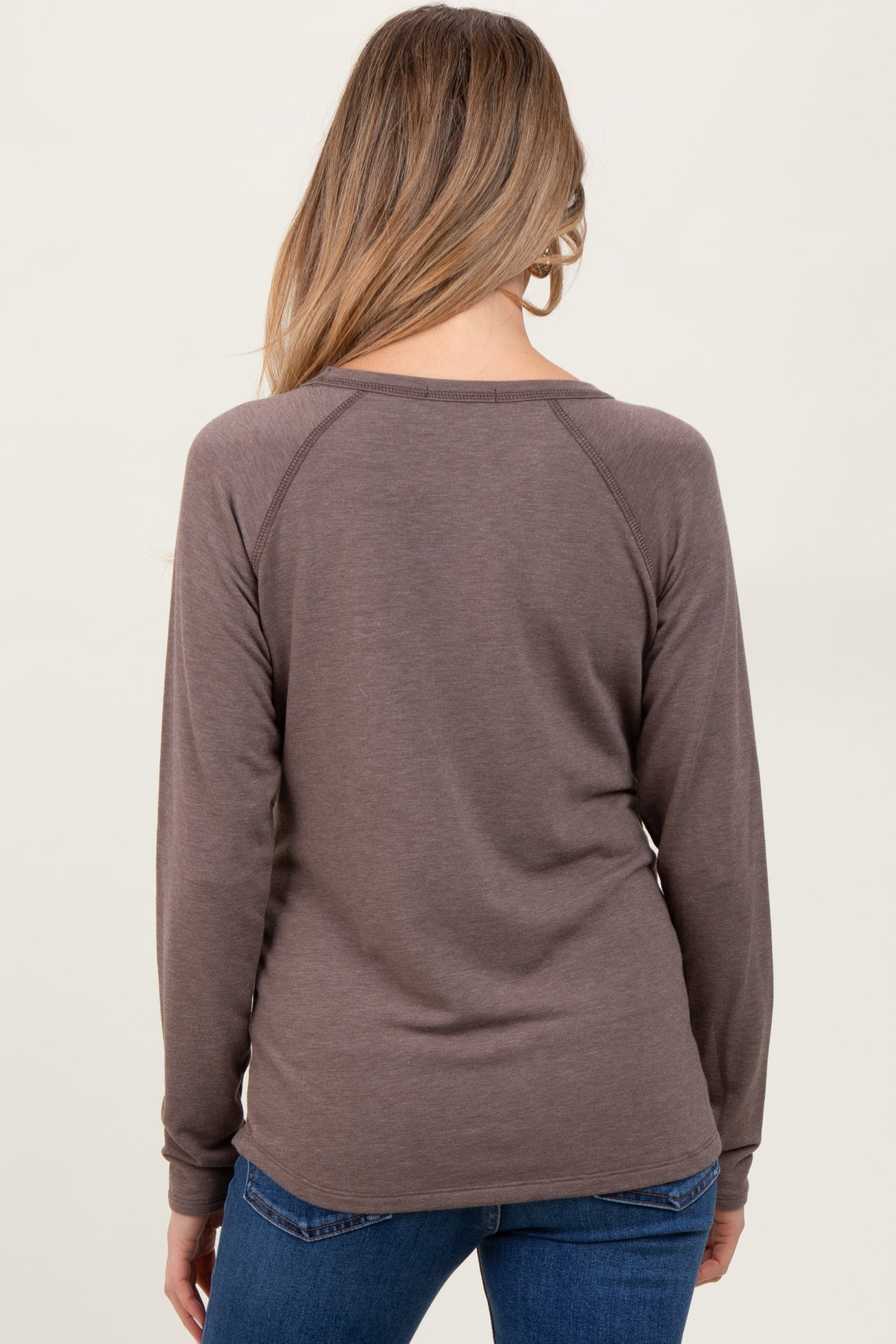 woman wearing a dark brown long sleeve maternity top with a fitted silhouette and raglan sleeves, showing the back view