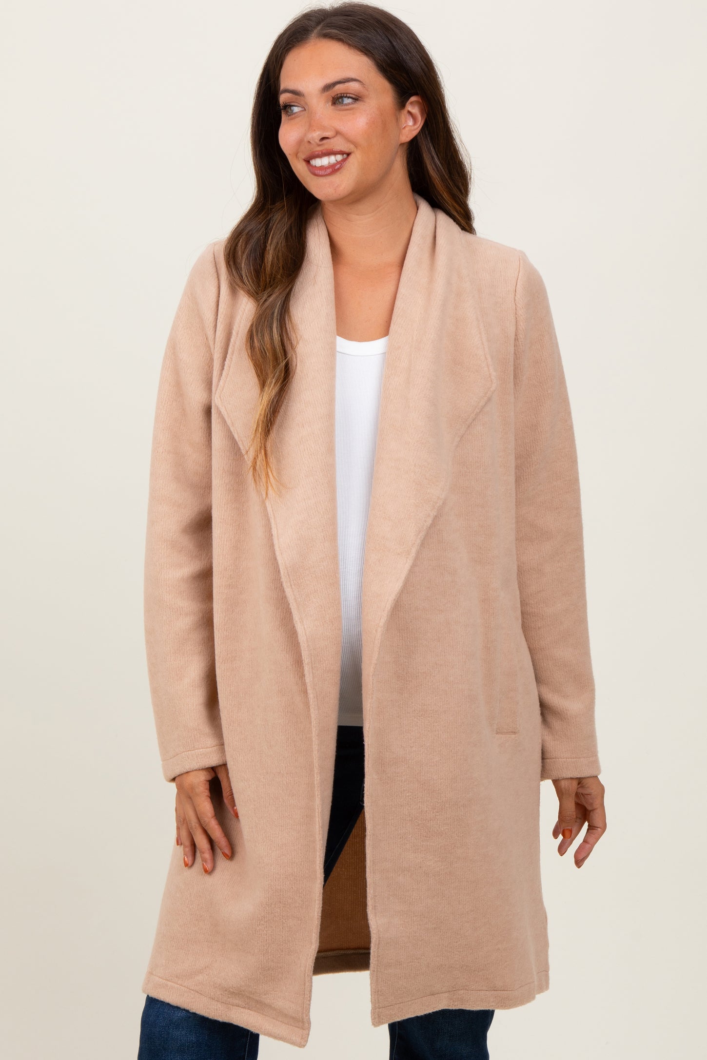 woman wearing a blush pink maternity coat with an open front and long sleeves