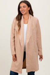 woman wearing a blush pink maternity coat with an open front and long sleeves