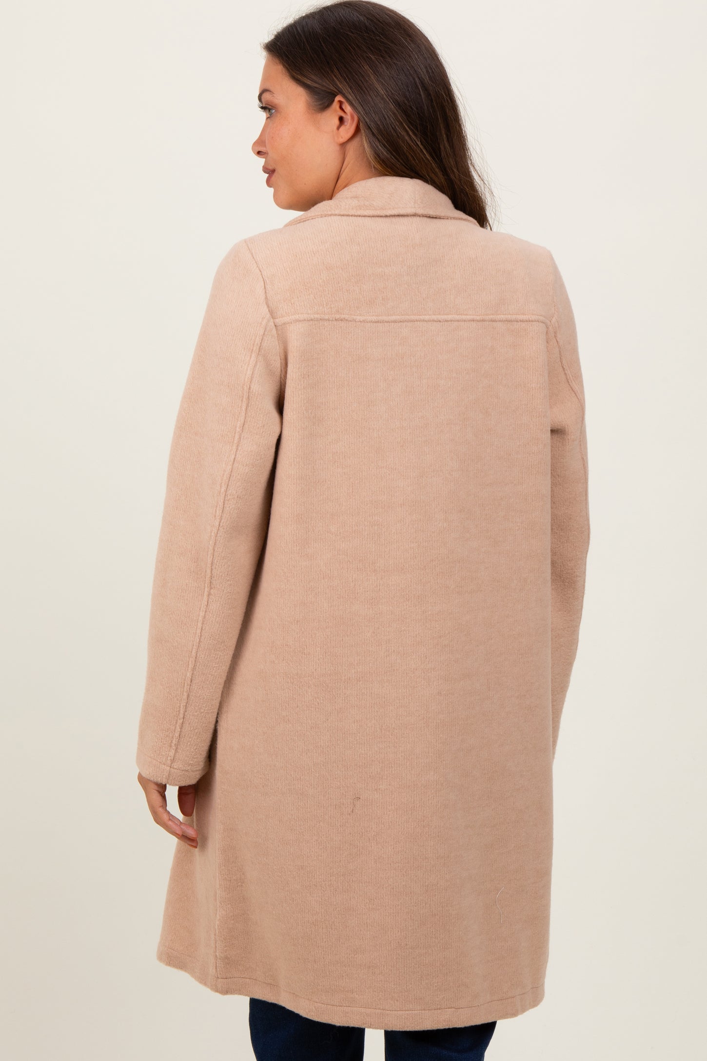 woman wearing a soft beige maternity coat seen from the back