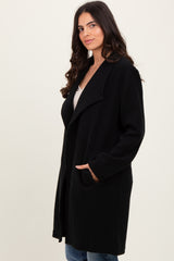 woman wearing a long black open-front coat with side pockets and a relaxed fit