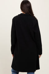woman wearing a black long coat, viewed from the back, paired with blue jeans