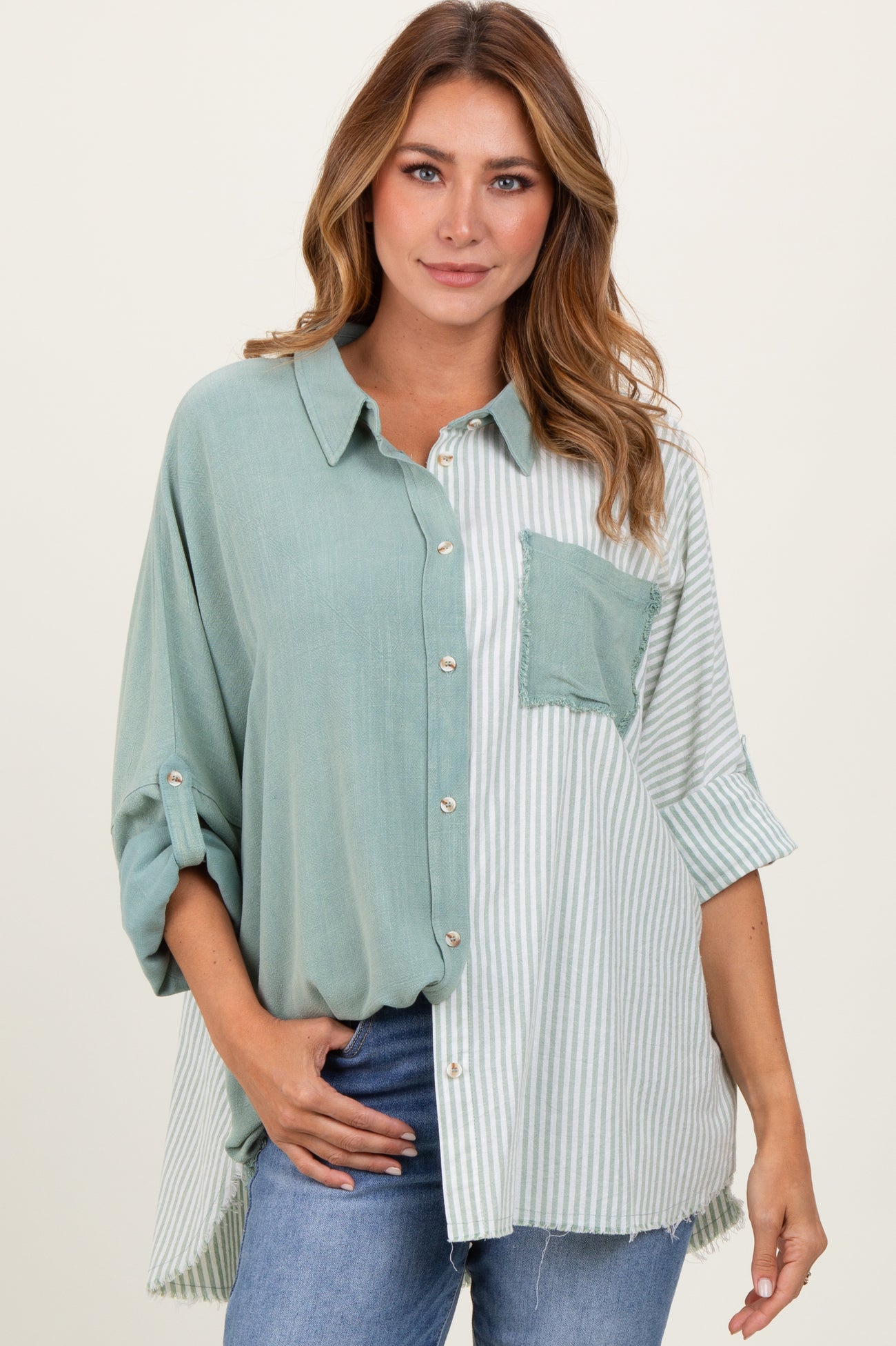 woman wearing a teal and striped oversized button-up shirt with a chest pocket and rolled sleeves