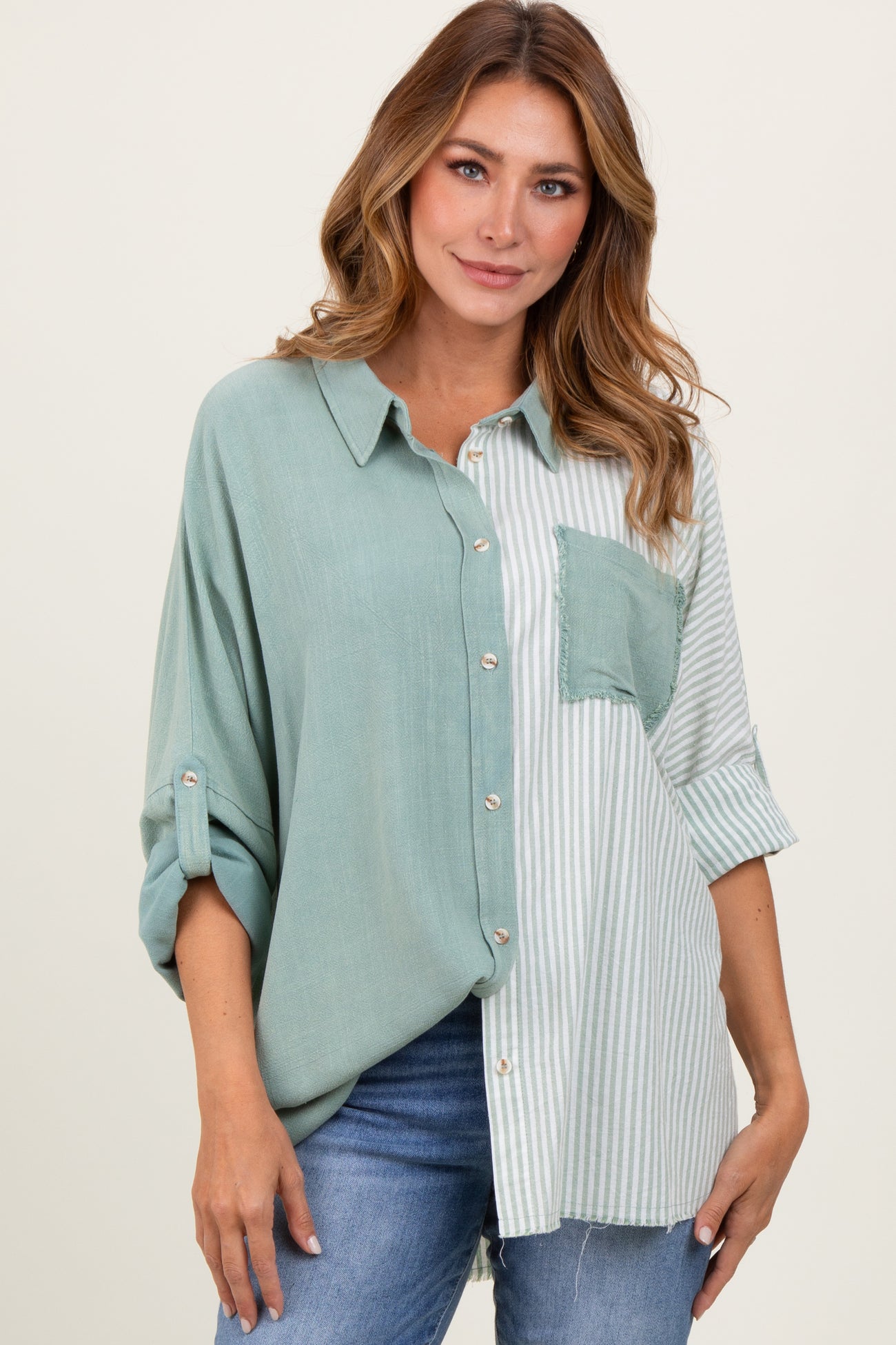 woman wearing a mint green and striped button-up shirt with a front pocket and rolled-up sleeves