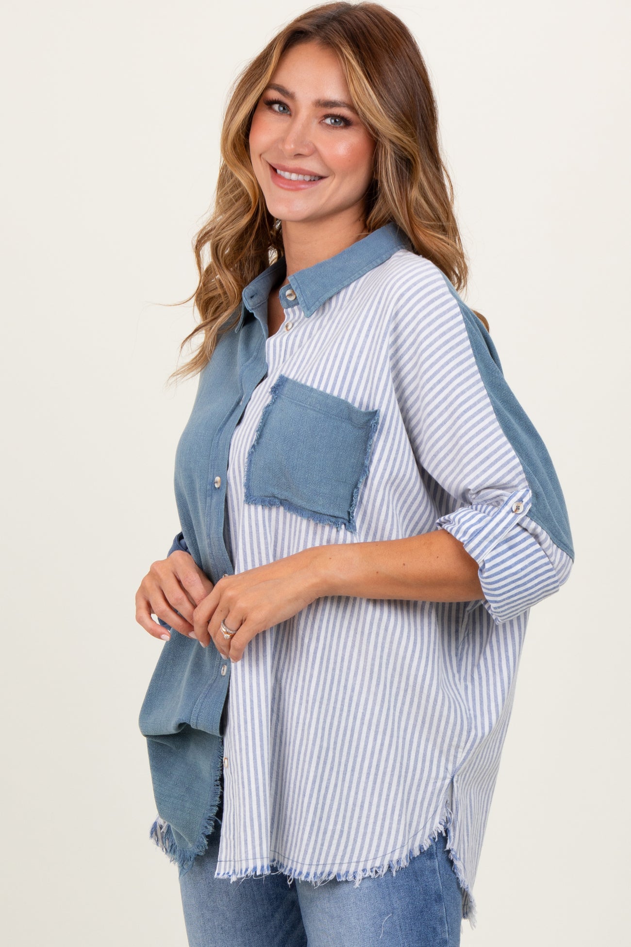woman wearing a blue and white striped button-up shirt with a distressed pocket and sleeves rolled up