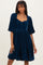 woman wearing a dark teal velvet short dress with puff sleeves and a fitted bodice, styled with a square neckline