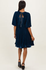 woman wearing a navy blue velvet dress with short puff sleeves and a bow detail at the back