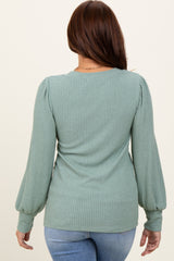 woman wearing a green ribbed long sleeve top with puff sleeves, seen from the back