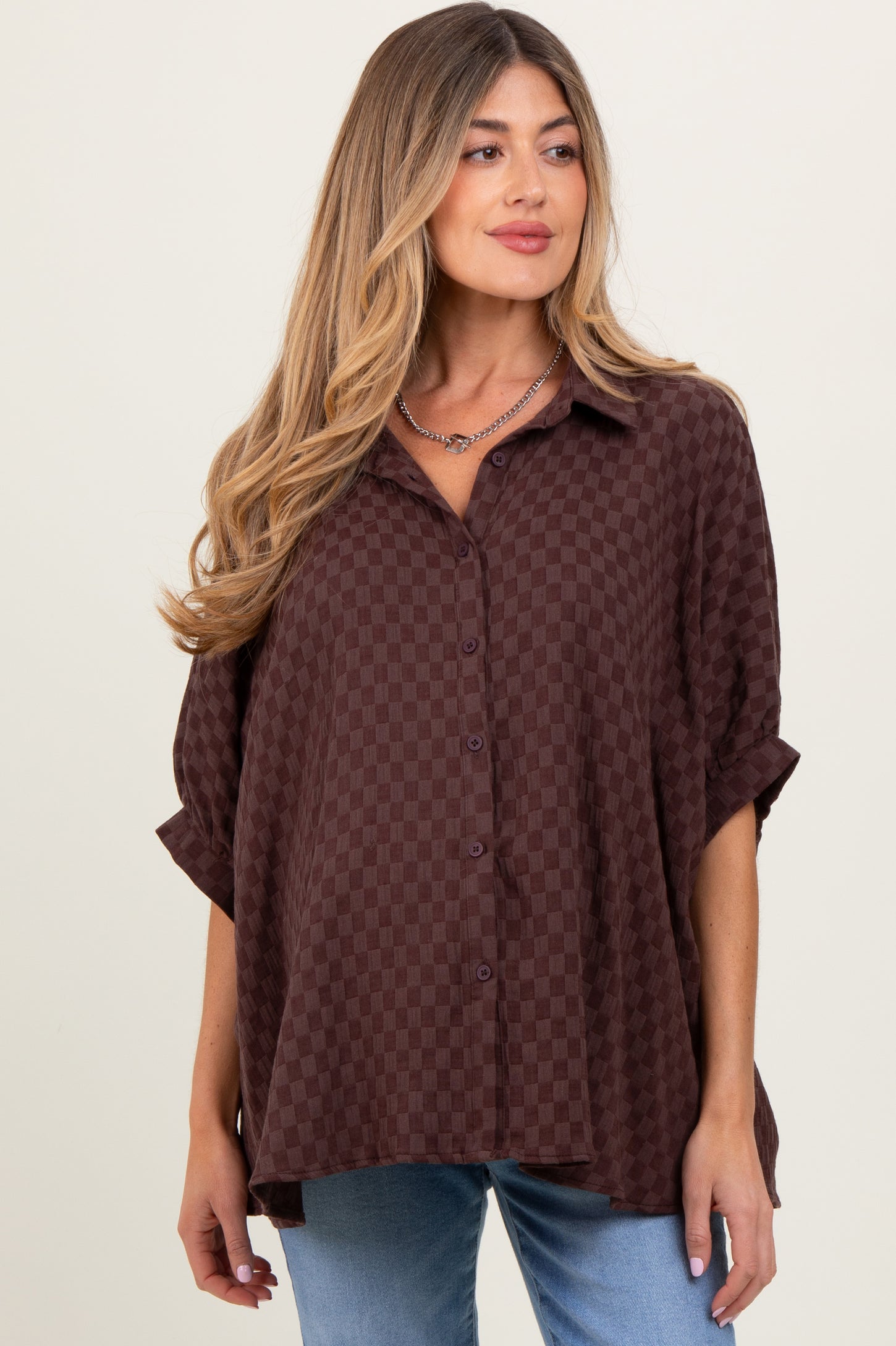 woman wearing a maroon checkered maternity shirt with rolled sleeves and a relaxed fit, showing her baby bump