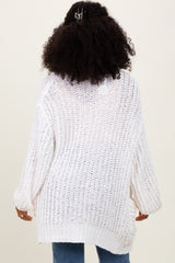 woman wearing a white oversized knit sweater with wide sleeves, shown from the back