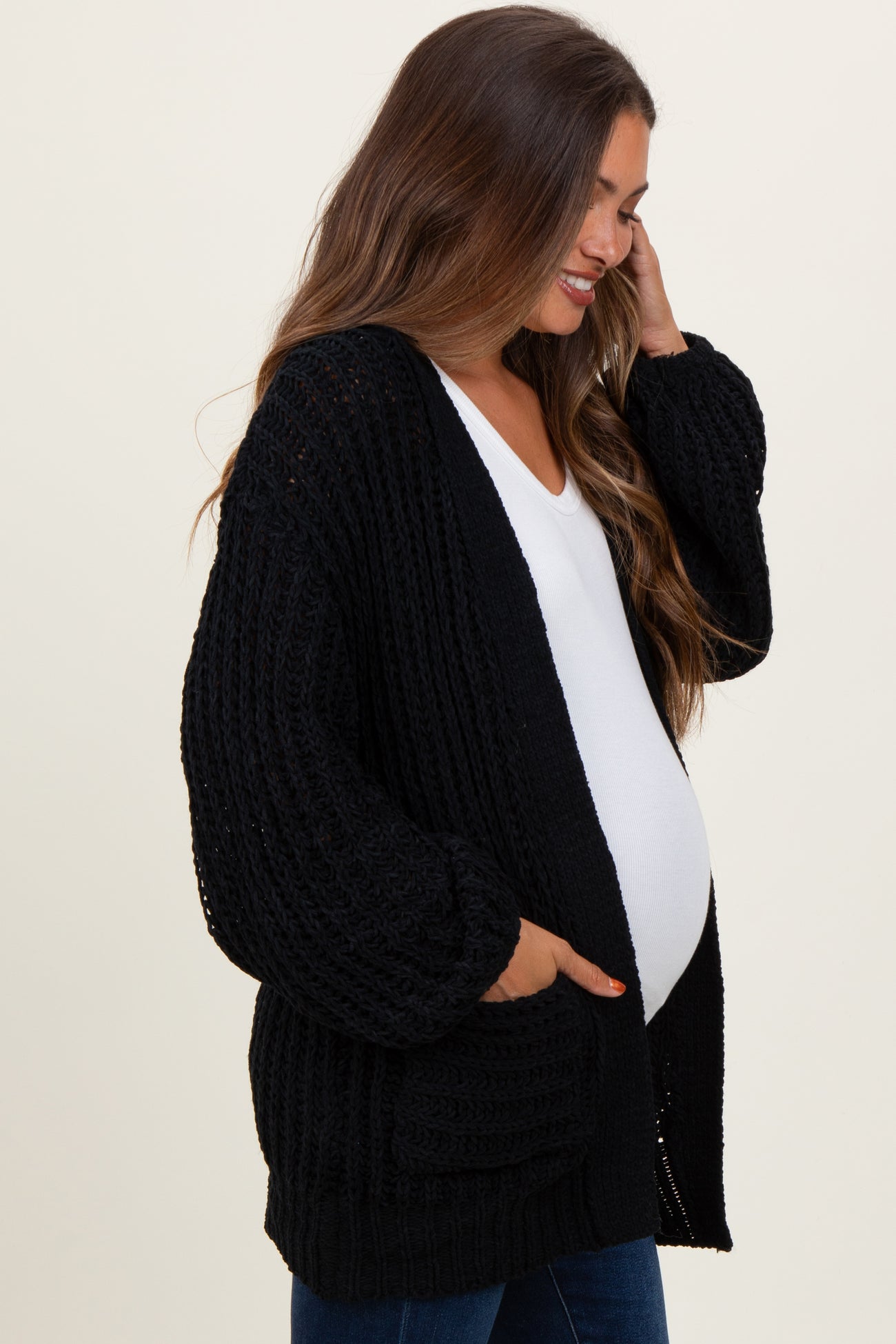 woman wearing a black knitted maternity cardigan and holding her baby bump