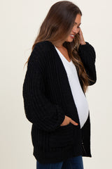 woman wearing a black knitted maternity cardigan and holding her baby bump