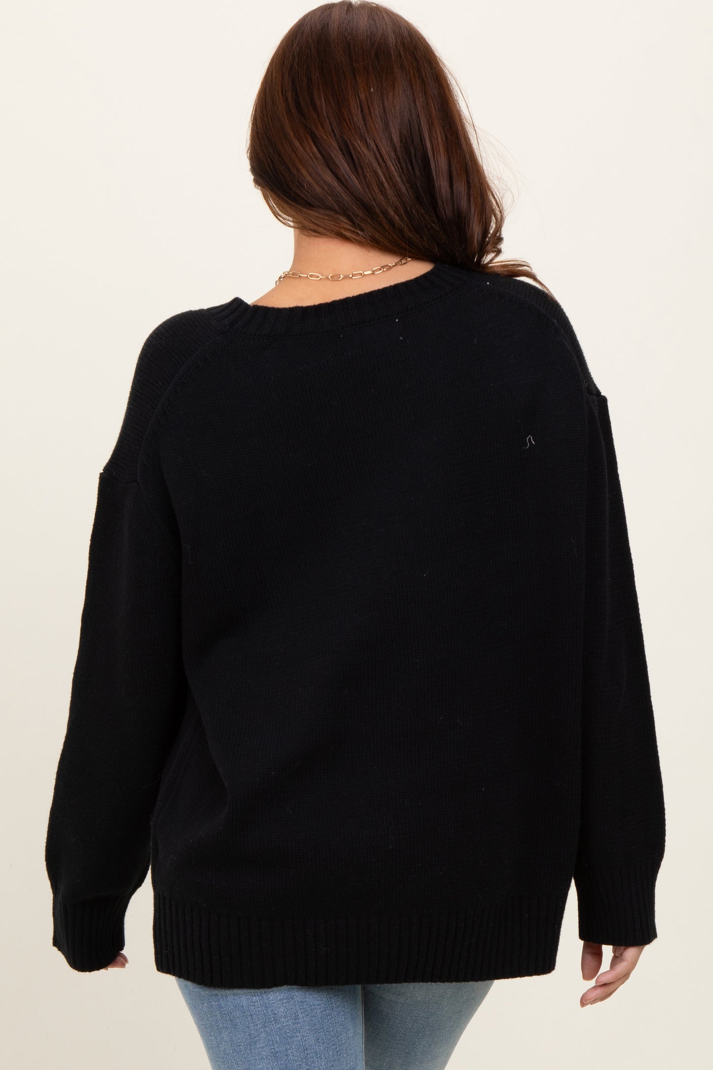 woman wearing a black oversized sweater from the back with long sleeves and a relaxed fit
