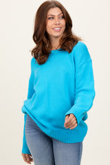woman wearing a bright turquoise oversized sweater with ribbed hem and cuffs, paired with light blue jeans