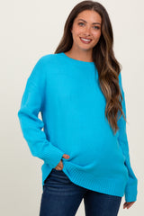 woman wearing a bright blue oversized maternity sweater with side slits and a relaxed fit, showcasing her baby bump