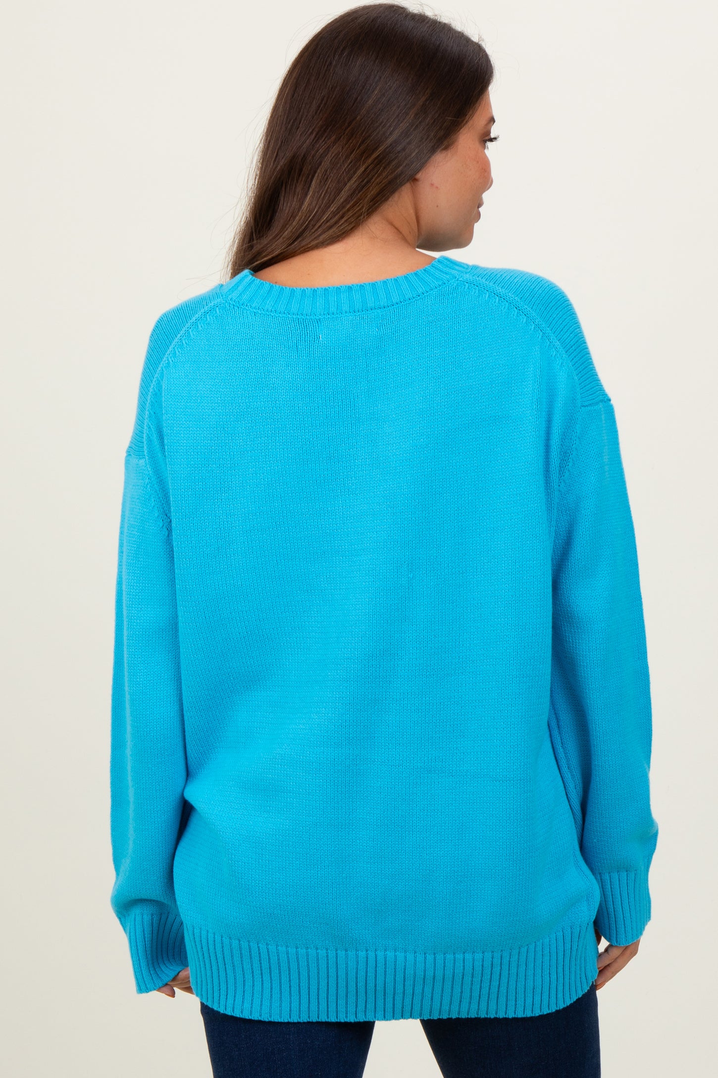 woman wearing a bright blue oversized maternity sweater, showing the back view and relaxed fit
