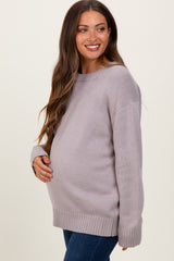 woman wearing a light grey maternity sweater with a relaxed fit and holding her baby bump