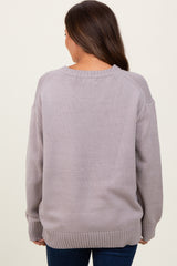 woman wearing a light gray oversized maternity sweater with a round neckline and ribbed cuffs, seen from the back