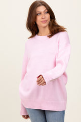 woman wearing a light pink oversized sweater with ribbed hem and sleeves, paired with blue jeans