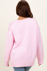 woman wearing a pink oversized knit sweater, seen from the back, paired with light blue jeans