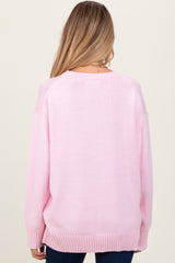 woman wearing a light pink oversized maternity sweater, shown from the back