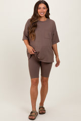 woman wearing a taupe maternity t-shirt and matching bike shorts, standing confidently and smiling