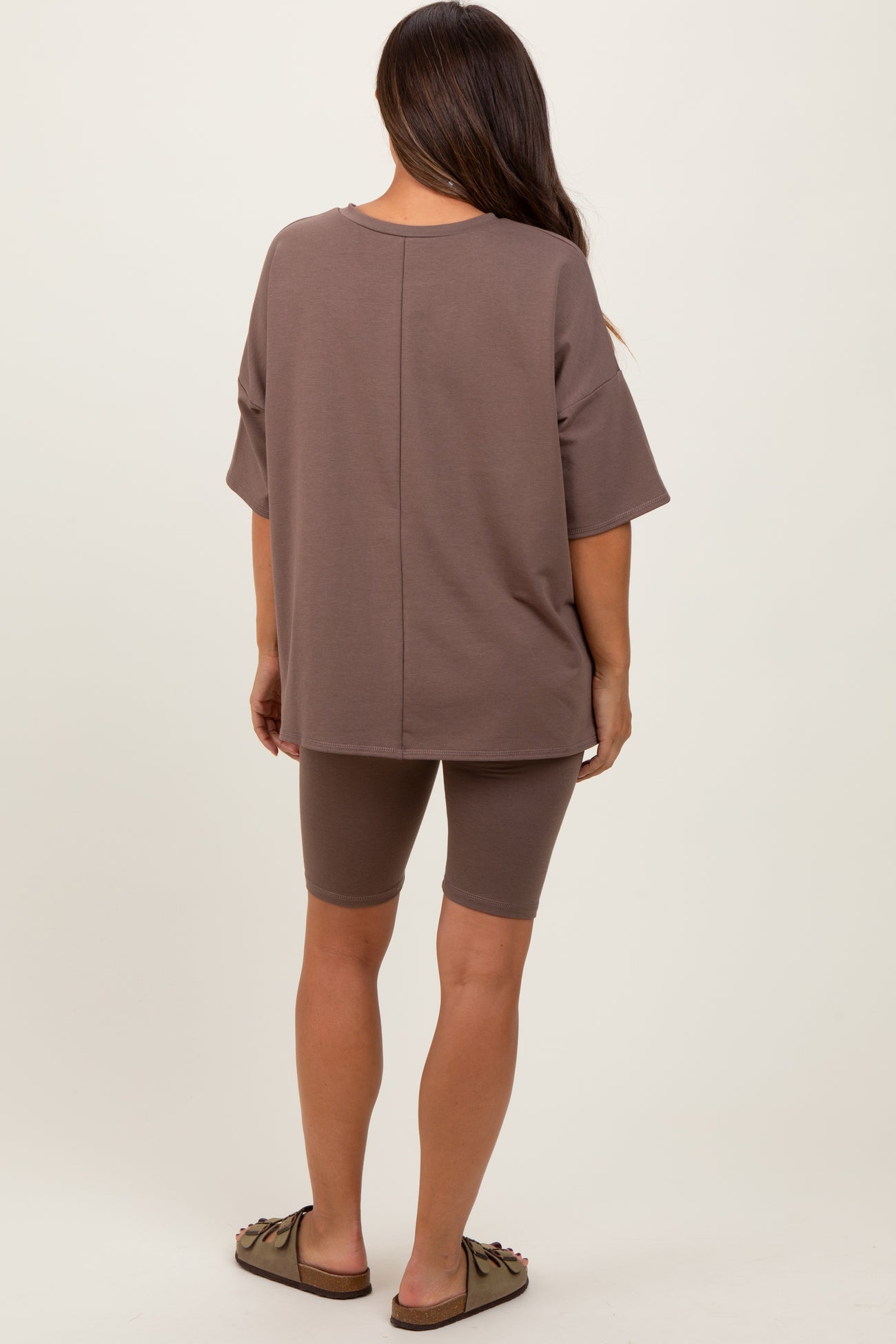 woman wearing a brown maternity oversized t-shirt and matching bike shorts, showing her back