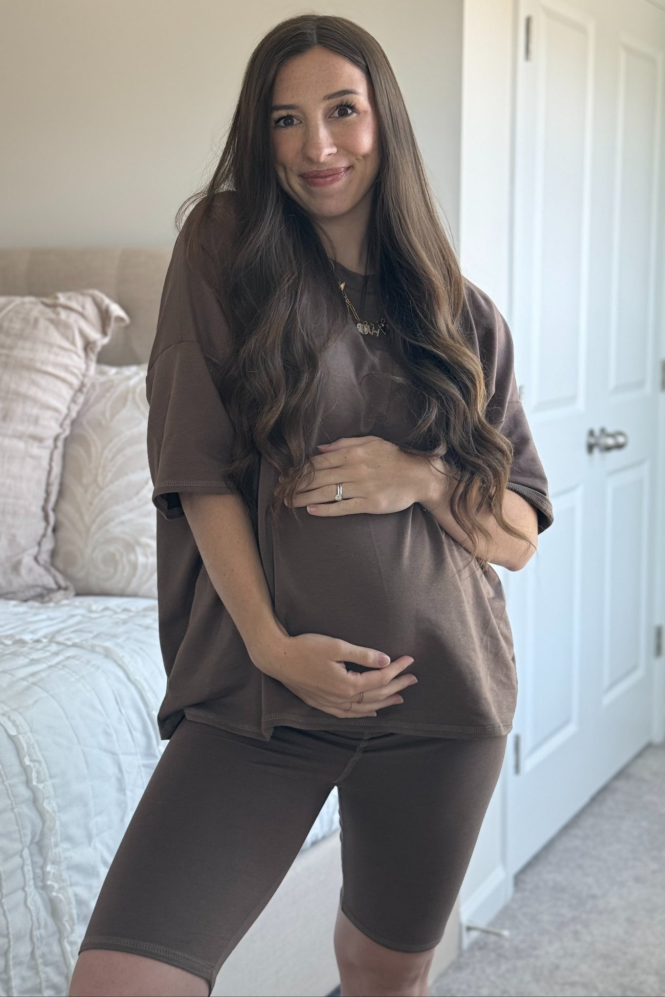 woman wearing a brown oversized t-shirt and matching bike shorts, showing her baby bump