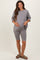 woman wearing a gray oversized maternity top and matching bike shorts, holding her baby bump