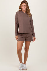 woman wearing a brown hooded sweatshirt with a front pocket and matching brown shorts, styled with white sneakers