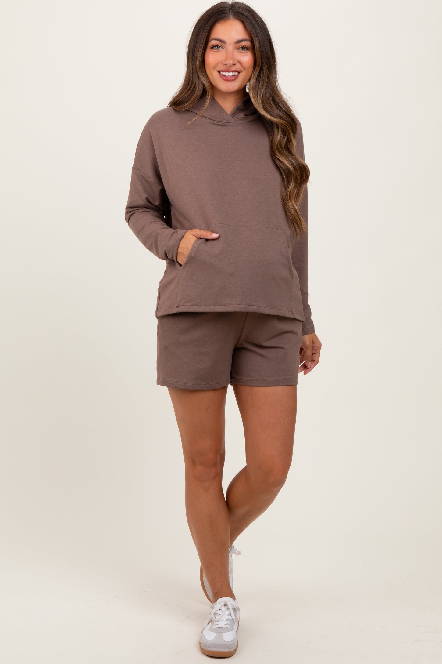 woman wearing a brown maternity hoodie with a front pocket and matching shorts