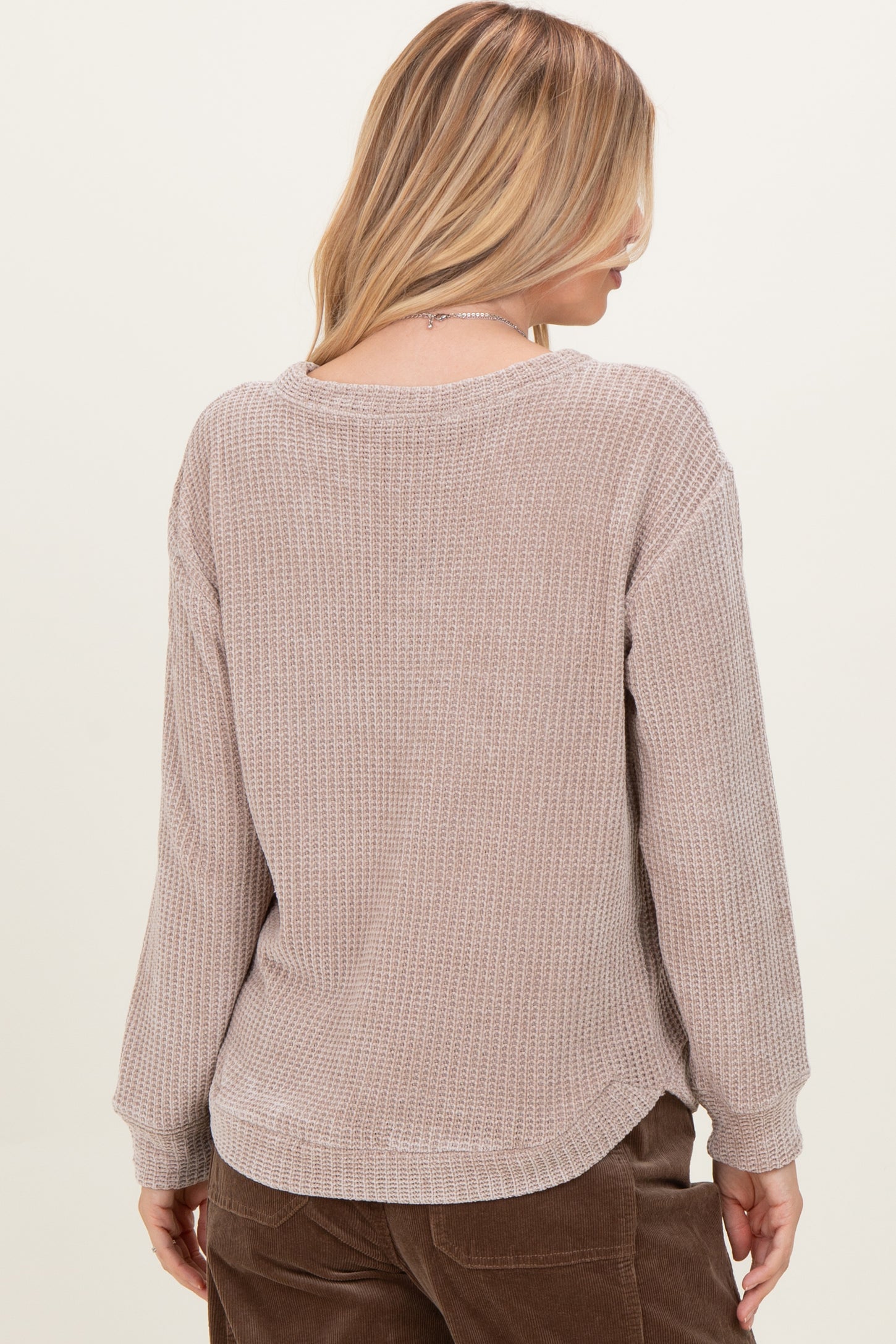 woman wearing a beige waffle knit long sleeve top, showing the back view and relaxed fit