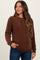 woman wearing a brown waffle knit maternity sweater and jeans, showing her baby bump