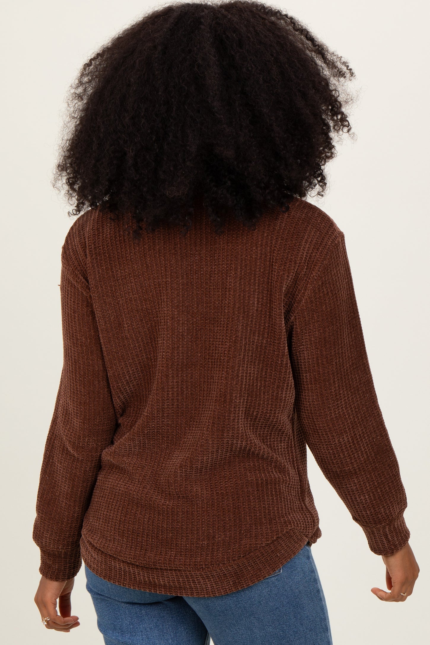 woman wearing a brown oversized waffle knit sweater with long sleeves and a relaxed fit, viewed from the back