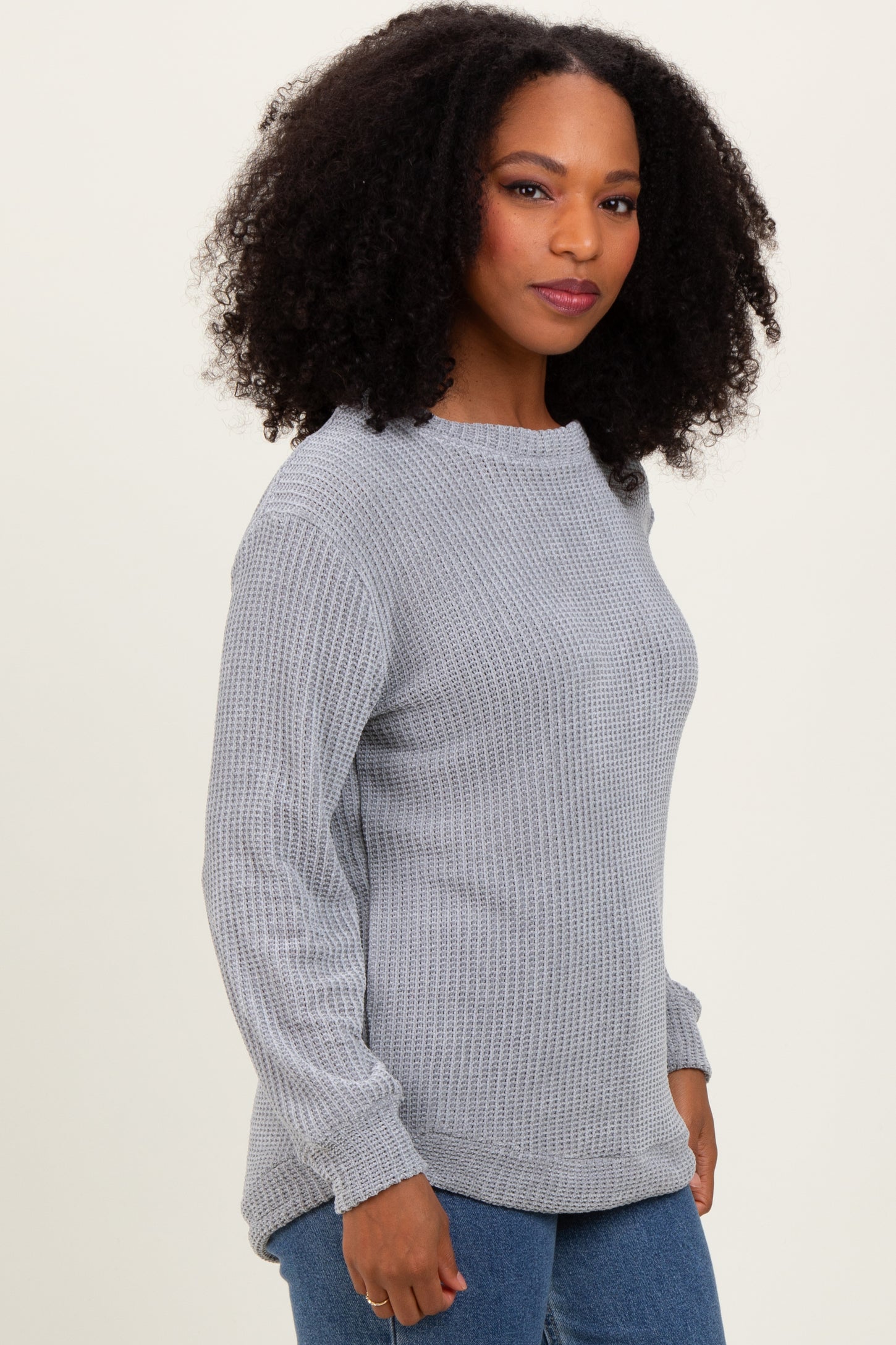 woman wearing a light gray textured long sleeve sweater with a relaxed fit and slight scoop neckline