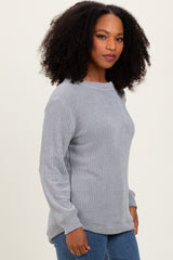 woman wearing a light gray textured long sleeve sweater with a relaxed fit and slight scoop neckline